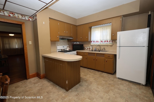 kitchen with white appliances, a peninsula, a sink, light countertops, and under cabinet range hood