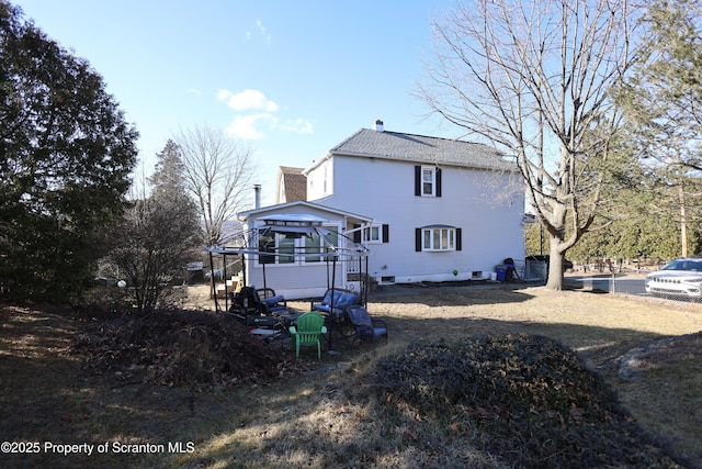 rear view of house with a shingled roof, a deck, stairway, and a chimney