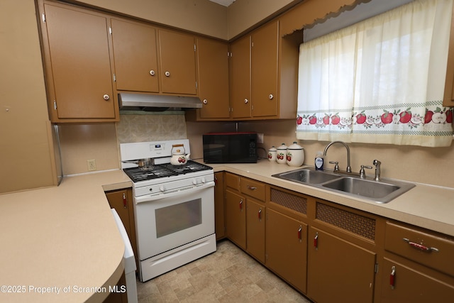 kitchen featuring under cabinet range hood, a sink, black microwave, light countertops, and white gas range