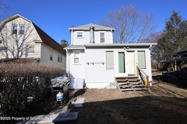 back of house featuring entry steps, roof with shingles, and fence