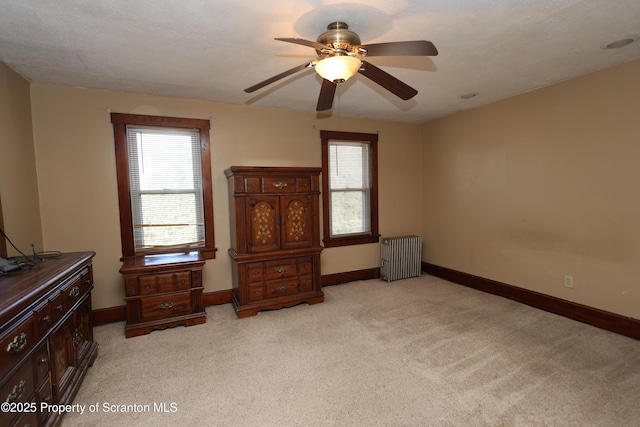 bedroom with ceiling fan, radiator heating unit, baseboards, and light carpet