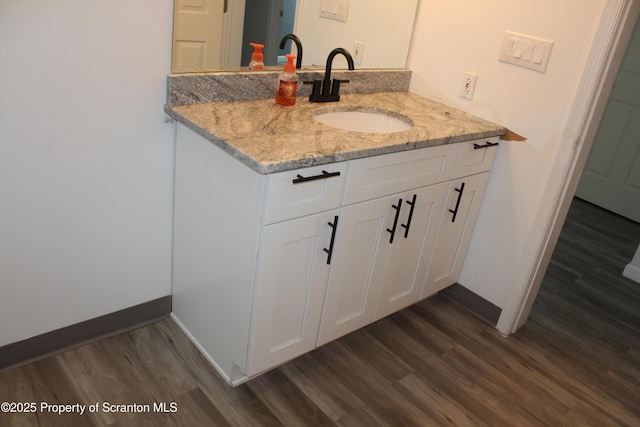 bathroom featuring baseboards, wood finished floors, and vanity