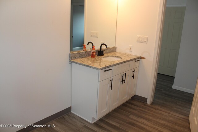 bathroom featuring vanity, baseboards, and wood finished floors