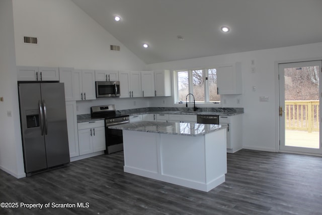 kitchen featuring light stone counters, visible vents, a kitchen island, a sink, and stainless steel appliances