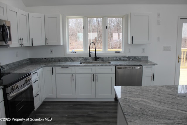 kitchen featuring dark wood-style floors, light stone countertops, appliances with stainless steel finishes, and a sink