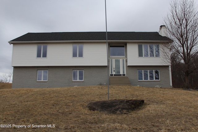 view of front of home featuring a front lawn, brick siding, a chimney, and entry steps