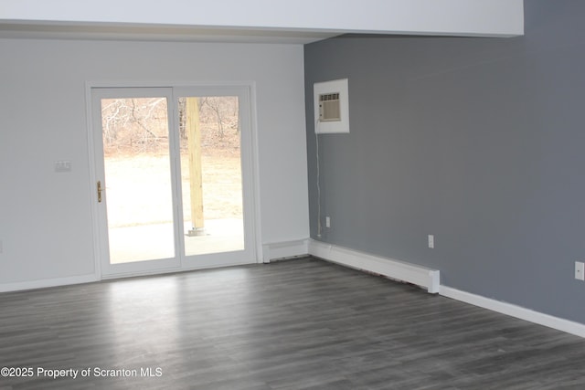 unfurnished room with a wall unit AC, a healthy amount of sunlight, dark wood-style flooring, and baseboards