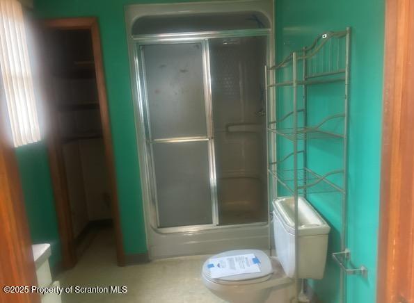 bathroom featuring a stall shower and toilet