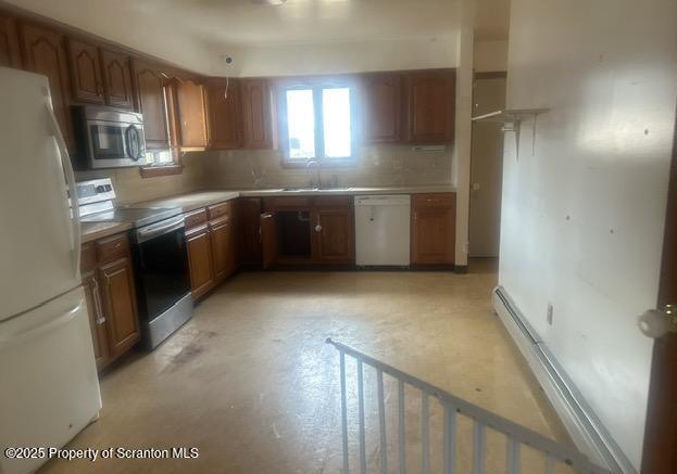 kitchen featuring brown cabinets, a sink, appliances with stainless steel finishes, light countertops, and decorative backsplash