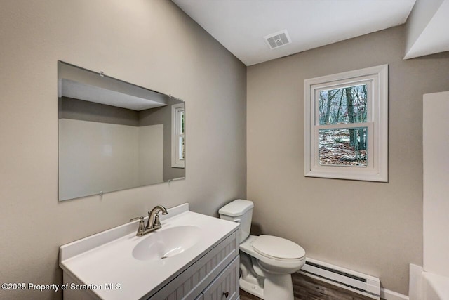 bathroom featuring toilet, vanity, and a baseboard heating unit