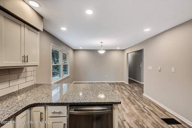 kitchen featuring hanging light fixtures, stainless steel dishwasher, backsplash, dark stone countertops, and light wood-type flooring