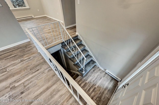 stairway featuring hardwood / wood-style flooring and a baseboard heating unit