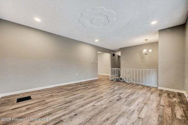 spare room with light hardwood / wood-style flooring and a notable chandelier