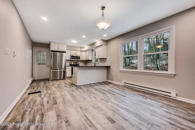 kitchen with light wood-type flooring, appliances with stainless steel finishes, a baseboard radiator, decorative light fixtures, and white cabinetry