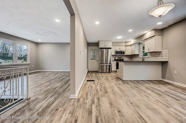 kitchen with backsplash, light hardwood / wood-style flooring, decorative light fixtures, white cabinetry, and stainless steel appliances