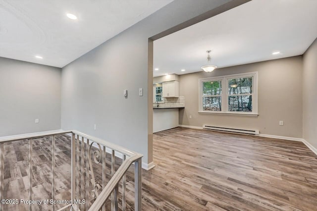 spare room featuring baseboard heating and light hardwood / wood-style flooring