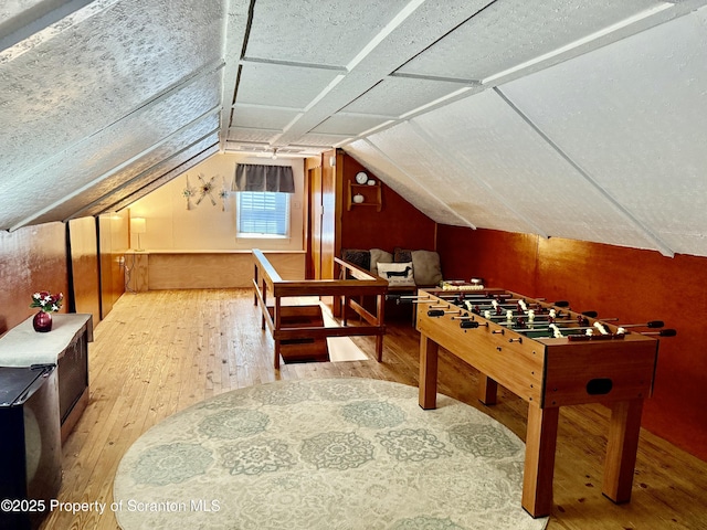 recreation room with hardwood / wood-style floors and lofted ceiling