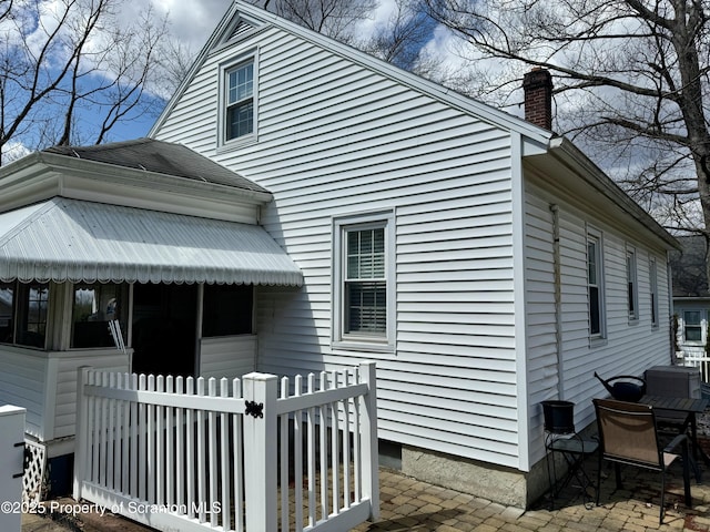 exterior space featuring a patio, roof with shingles, fence, and a chimney