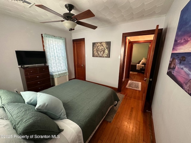 bedroom with visible vents, ceiling fan, wood-type flooring, and baseboards