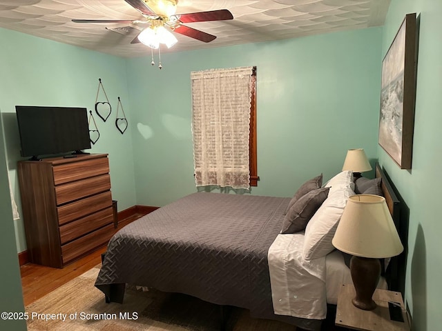bedroom with baseboards, a ceiling fan, and wood finished floors