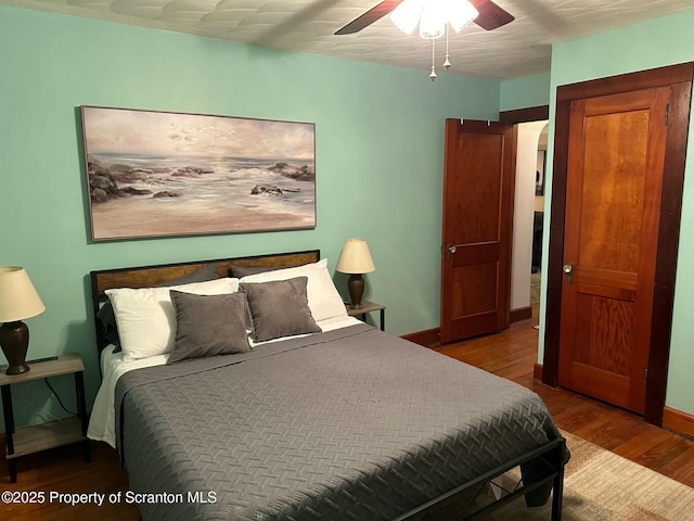 bedroom with wood finished floors, baseboards, and a ceiling fan