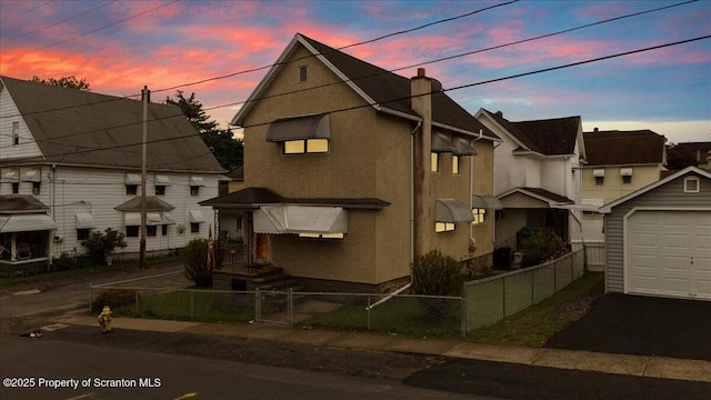 multi unit property featuring a garage, stucco siding, a chimney, aphalt driveway, and a fenced front yard