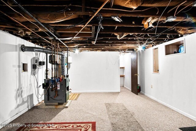 basement with a heating unit, carpet flooring, and baseboards