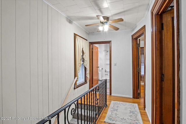 corridor featuring crown molding, light wood-type flooring, and baseboards