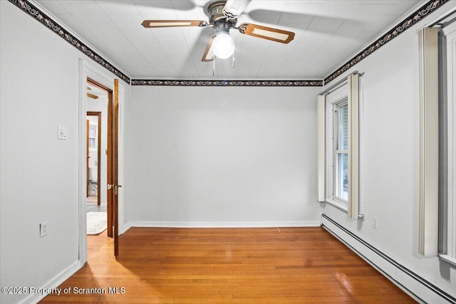 spare room featuring a baseboard radiator, ornamental molding, a ceiling fan, and wood finished floors