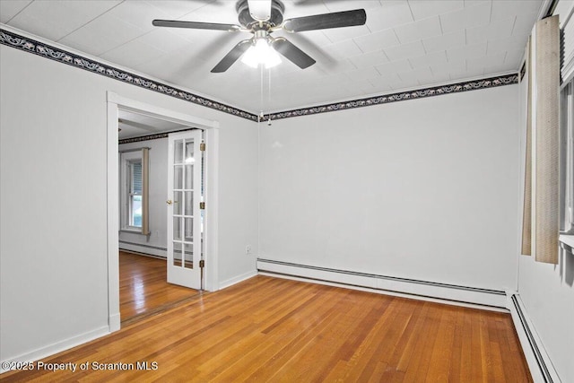 spare room with ceiling fan, light wood-style flooring, and a baseboard heating unit