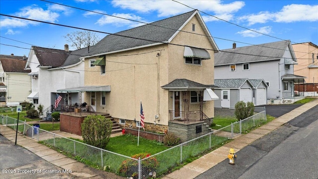 view of front of home featuring a residential view, a garage, stucco siding, a fenced backyard, and driveway