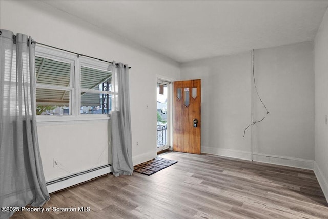 empty room with baseboards, a baseboard radiator, and wood finished floors