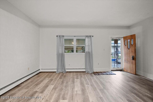 unfurnished room with baseboards, baseboard heating, and wood finished floors