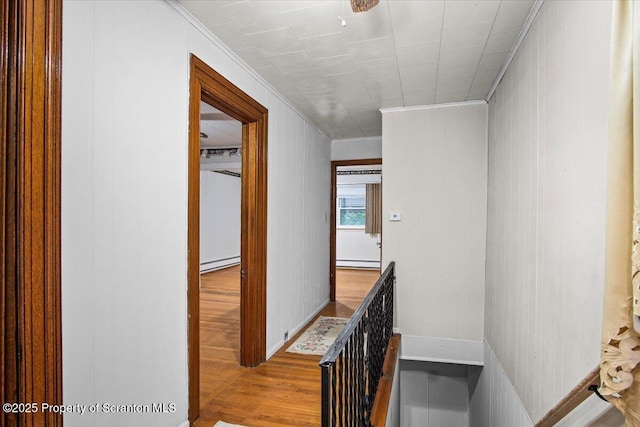 hallway with crown molding, baseboard heating, an upstairs landing, and wood finished floors