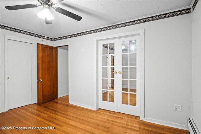 unfurnished bedroom with french doors, wood finished floors, a ceiling fan, baseboard heating, and baseboards