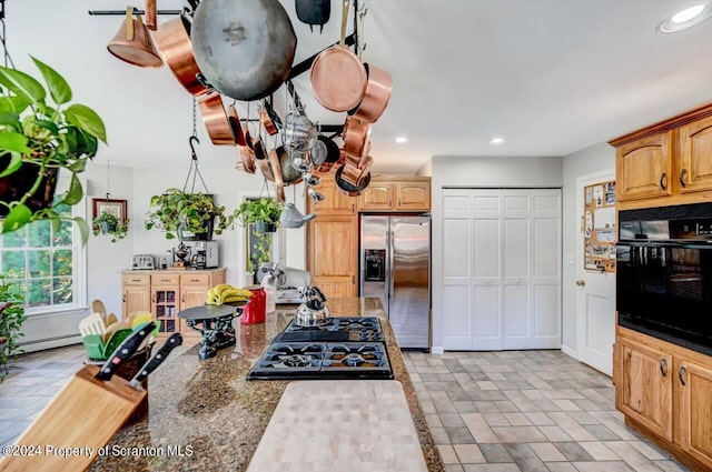 kitchen featuring dark stone counters, black appliances, and a baseboard heating unit