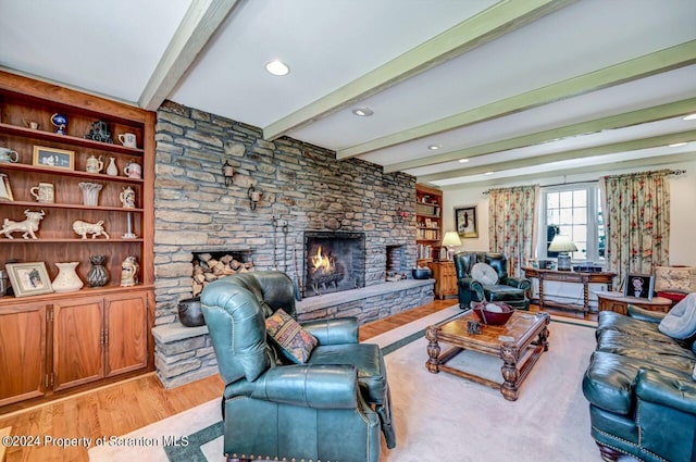 living room featuring a stone fireplace, built in shelves, beamed ceiling, and light wood-type flooring