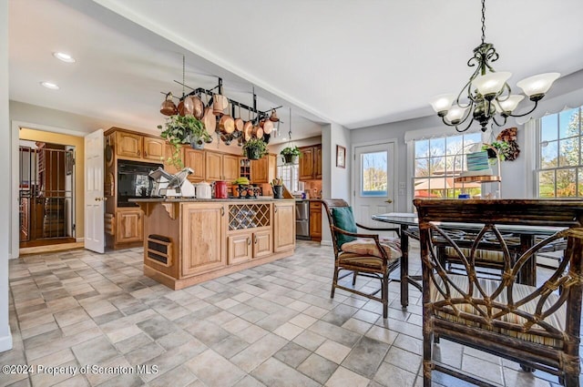 kitchen with a center island, stainless steel dishwasher, hanging light fixtures, and a notable chandelier