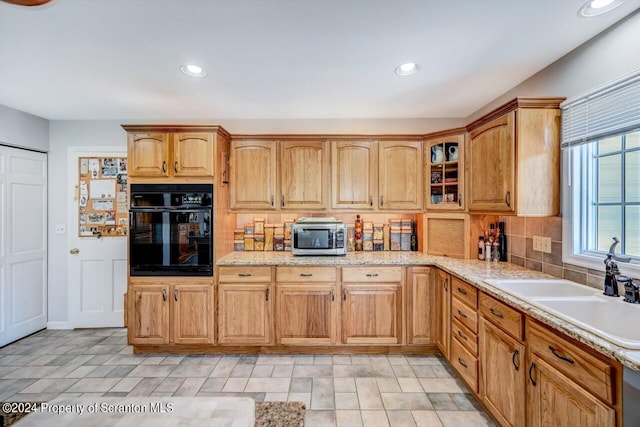 kitchen featuring backsplash, sink, light stone countertops, and stainless steel appliances