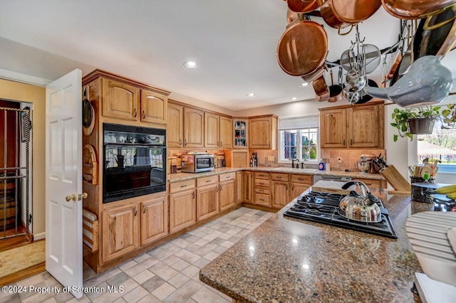 kitchen featuring stone counters, decorative backsplash, sink, and appliances with stainless steel finishes