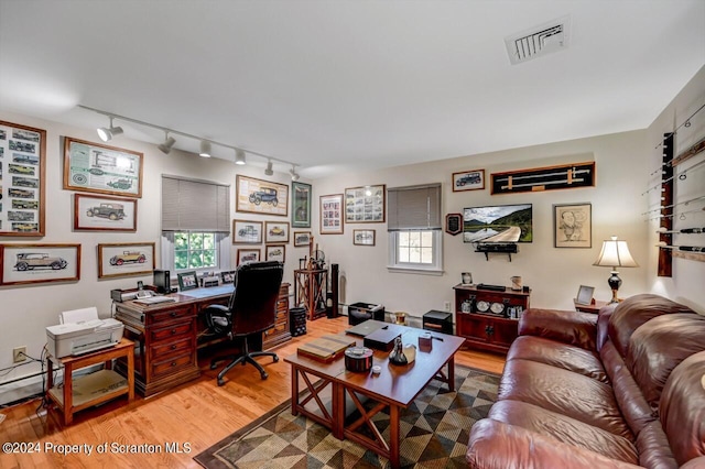 office with hardwood / wood-style flooring and track lighting