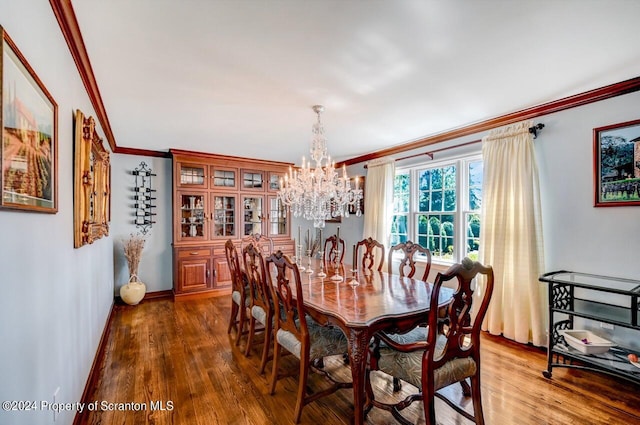 dining area featuring wood-type flooring, an inviting chandelier, and crown molding