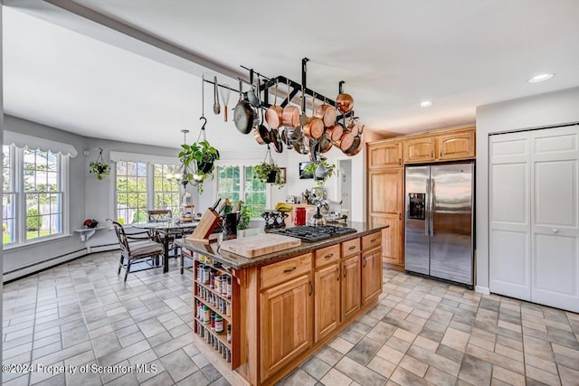 kitchen with stainless steel fridge, gas stovetop, a baseboard heating unit, an inviting chandelier, and a kitchen island