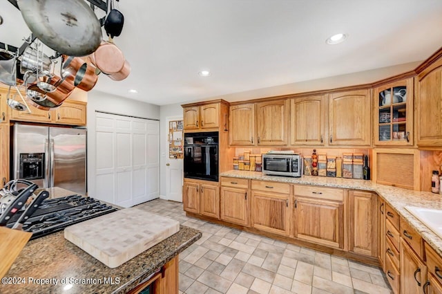 kitchen featuring light stone countertops, sink, and black appliances