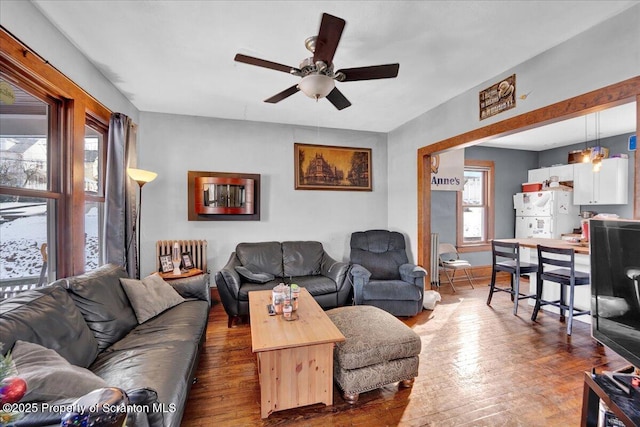 living room featuring radiator, dark wood-type flooring, plenty of natural light, and ceiling fan