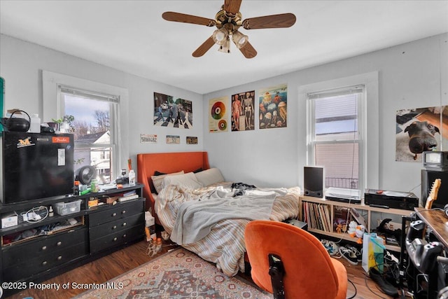 bedroom featuring multiple windows, hardwood / wood-style floors, and ceiling fan