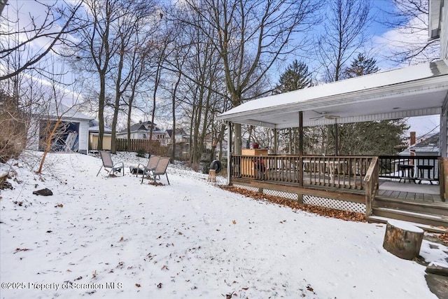 snowy yard with a wooden deck, ceiling fan, and a shed