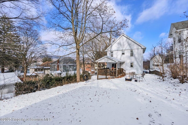 snow covered rear of property with a deck