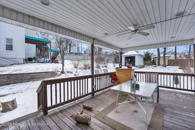 snow covered deck featuring ceiling fan and a shed