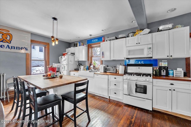 kitchen featuring white cabinetry, butcher block countertops, pendant lighting, and white appliances